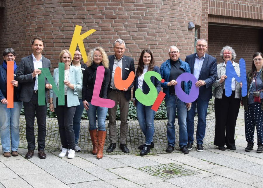 Das Foto zeigt eine Gruppe von Menschen, die das Wort "Inklusion" in einzelnen großen Buchstaben hochhalten.
