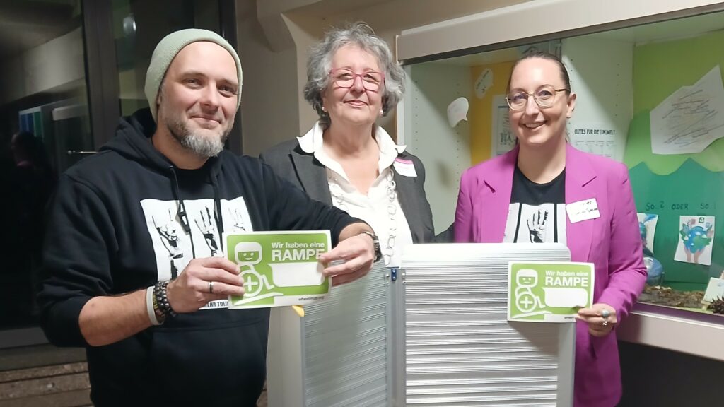 Das Foto zeigt drei Menschen hinter einer ausklappbaren Rampe.