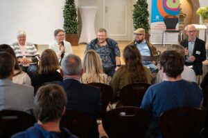 Das Foto zeigt eine Podiumsdiskussion aus Sicht des Publikums.